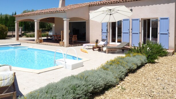 A poolside area with a covered patio, lounge chairs, and a table.