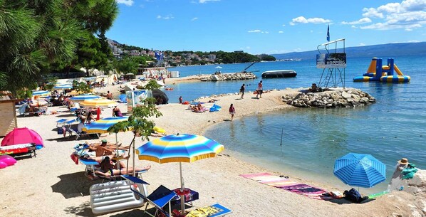 Relax by the beach with lounge chairs and umbrellas, enjoy the clear water and nearby amenities.