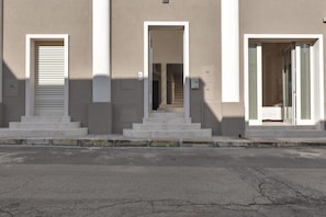 A building with three entrances, each with a set of steps leading to a door. - San Pancrazio Suite Apartments (San Pancrazio Salentino)