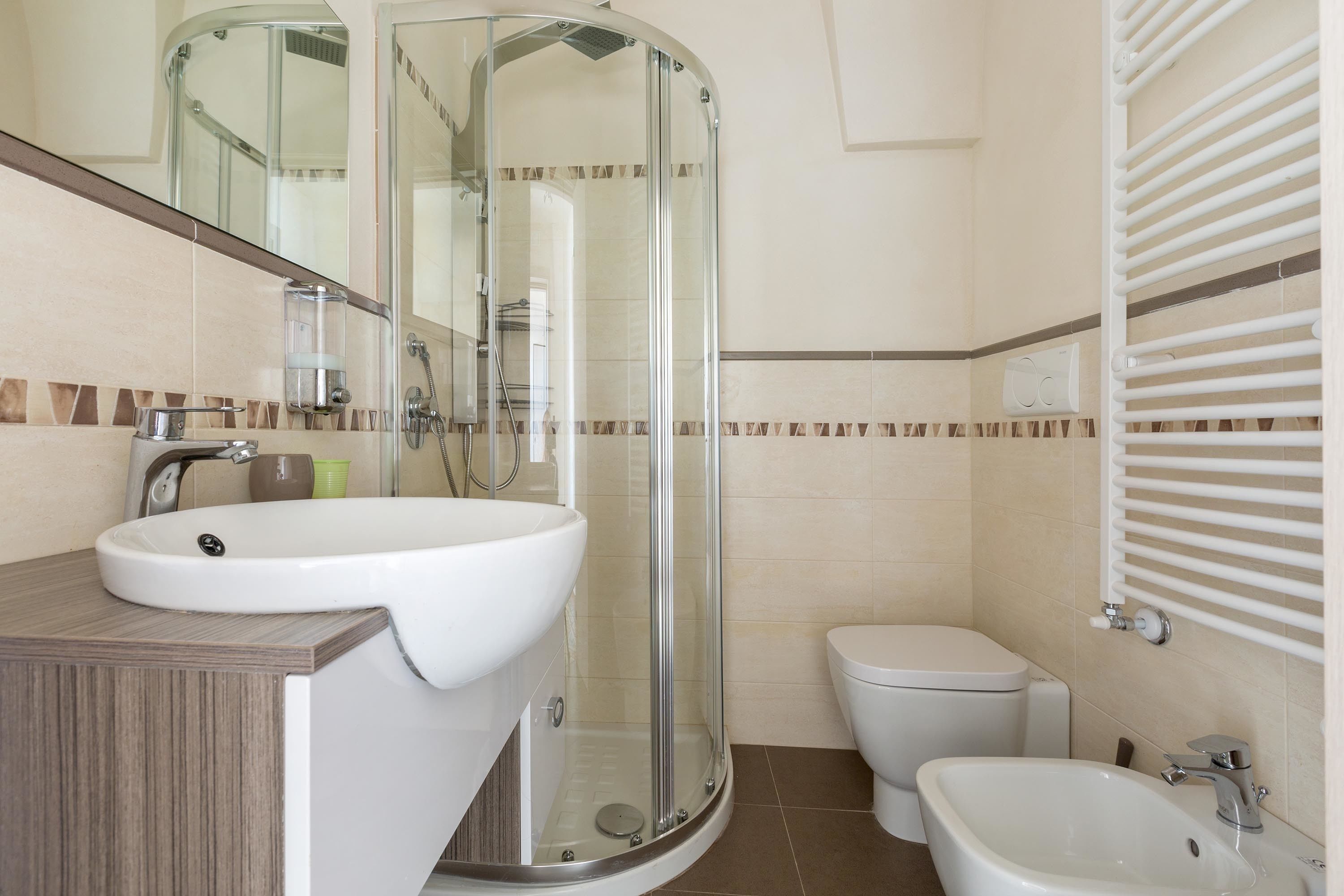Un baño moderno con cabina de ducha de vidrio, lavamanos, inodoro y bidé.
