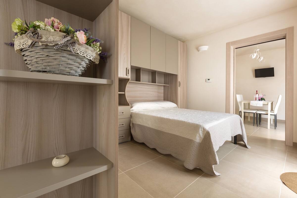 A modern bedroom with a bed, a vanity with a mirror, and a small table with chairs.