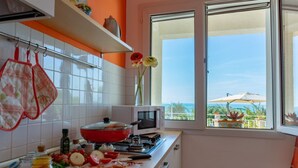 Una cucina con mobili bianchi, un piano cottura rosso e una finestra vista all'esterno.