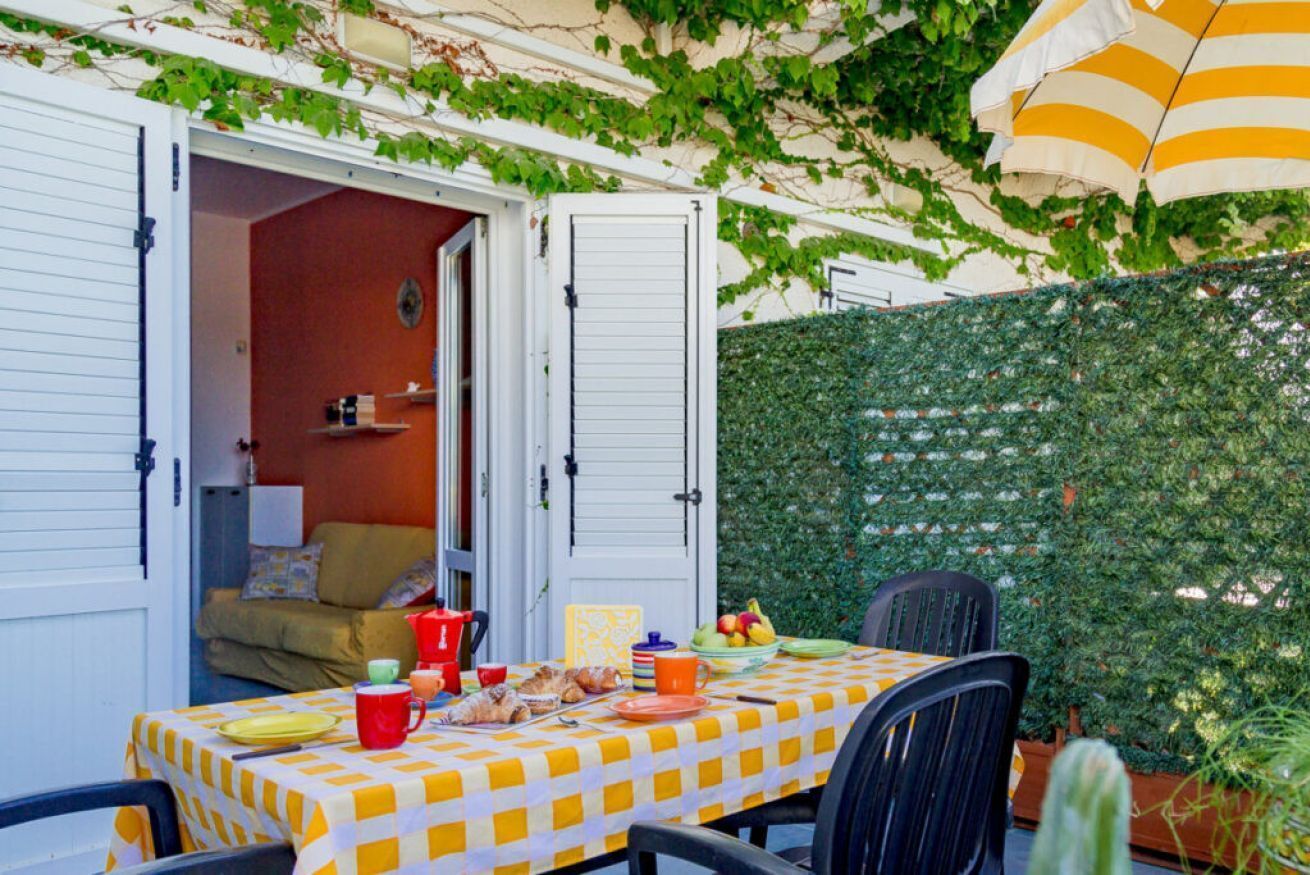 Un patio abierto con mantel a cuadros, una mesa de comedor, sillas y diversos alimentos.