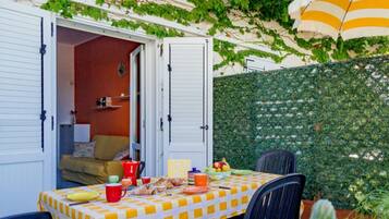 Un patio abierto con mantel a cuadros, una mesa de comedor, sillas y diversos alimentos.