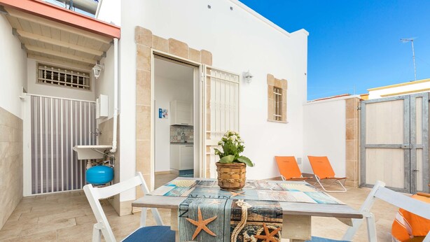 Un patio con tavolo, sedie e una pianta in vaso.