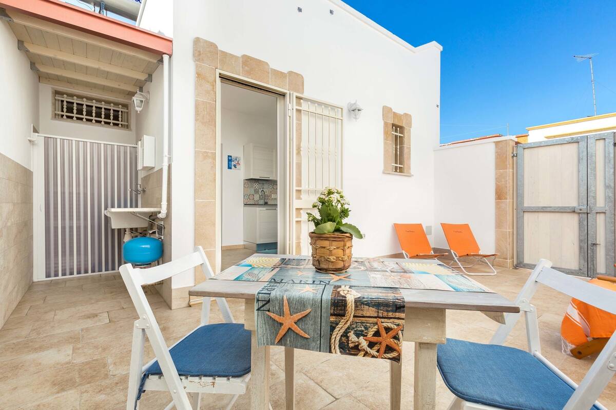 A patio with a table, chairs, and a potted plant.