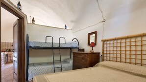 A dormitory room with bunk beds, a wooden dresser, a mirror, and a kitchen area visible through an open door. - Pajara Acquaviva (Castro)