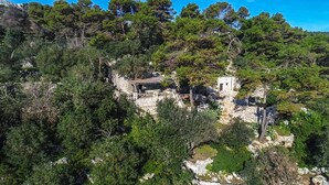 A stone building with a small annex, surrounded by dense greenery and trees. - Pajara Acquaviva (Castro)