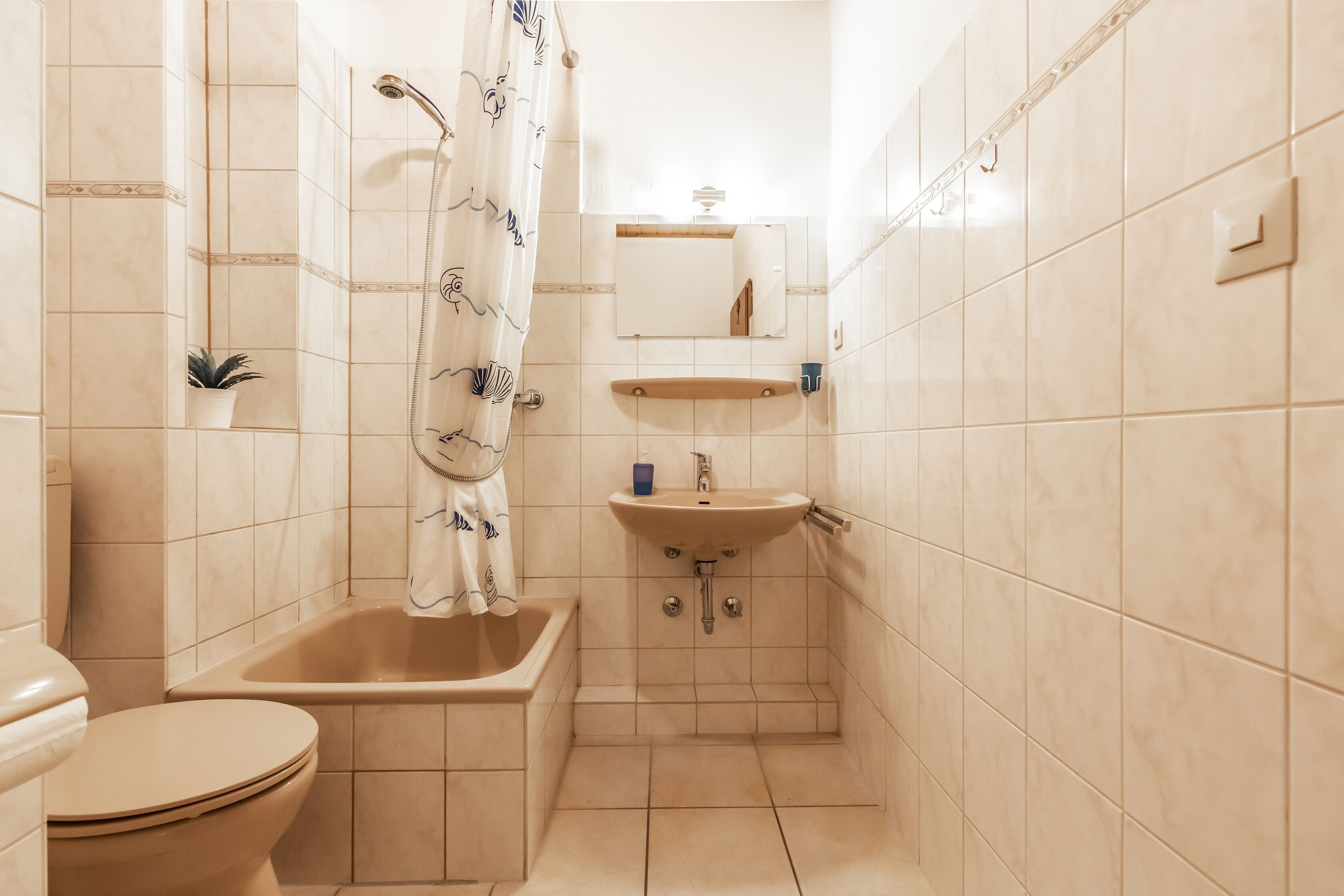 A small, compact bathroom with a toilet, sink, and shower.