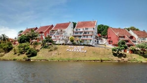 A coastal village with red-roofed buildings and a sign reading "VILLAGE DOS PASSAROS". - Village dos Pássaros (Guarapari)
