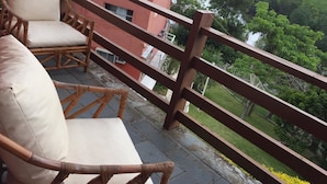 A balcony with wicker chairs and a wooden railing overlooking a lush green landscape. - Village dos Pássaros (Guarapari)