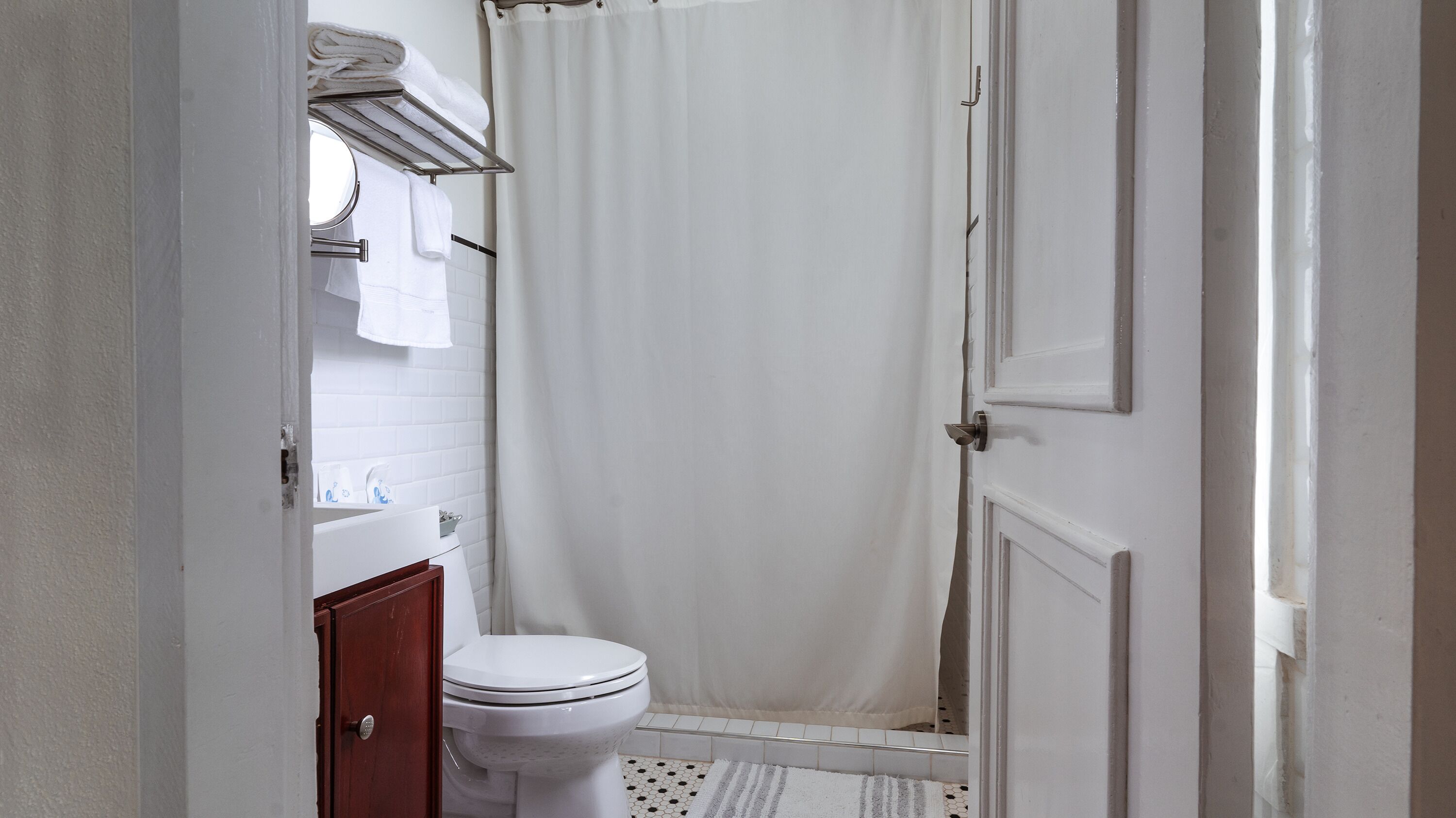 A bathroom with a toilet, a shower curtain, and a towel rack.