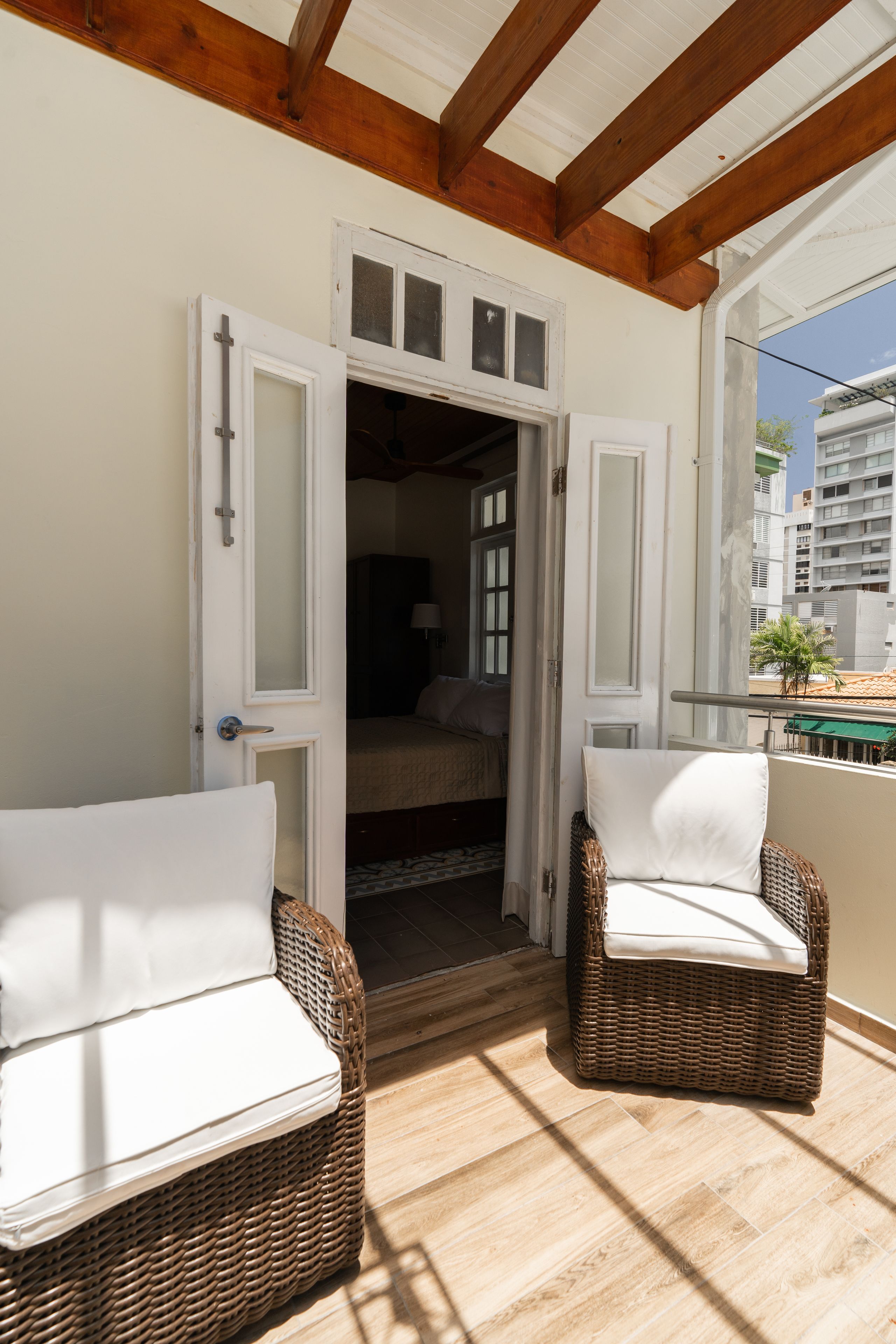 An open balcony with wicker chairs and a view of the interior.