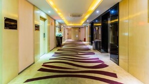 Ein Hotelgang mit einem zebra-gestreiften Teppich, eingelassener Beleuchtung und Glastüren auf der rechten Seite.