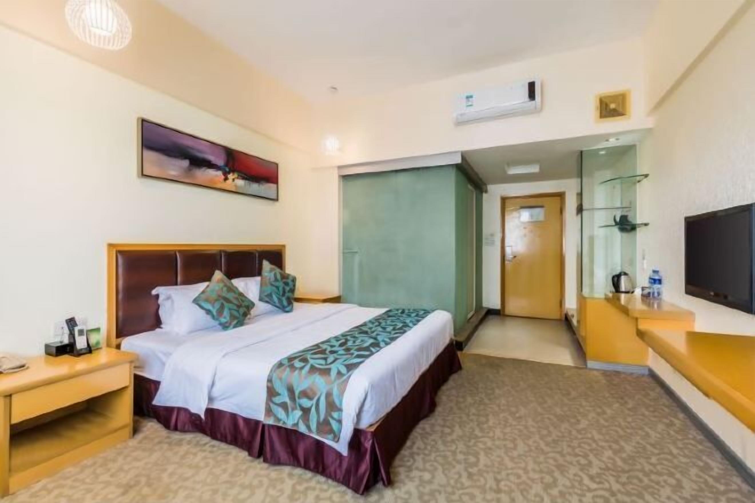 Una habitación de hotel con cama, mesita de noche y televisor.
