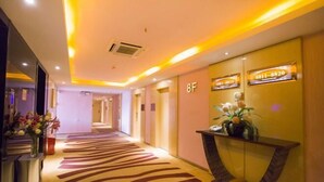 Ein Hotel-Empfangsbereich mit Teppichboden, einer Rezeption und einem an der Wand montierten Telefon.