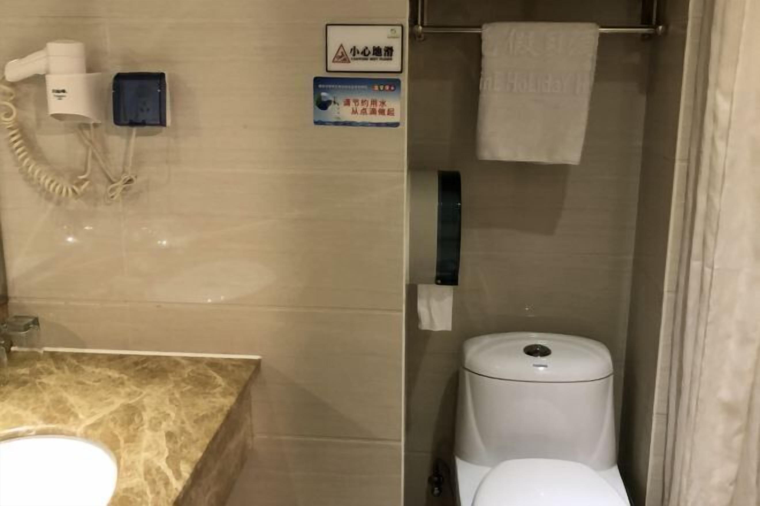 A bathroom with a toilet, a hand dryer, and a towel rack.