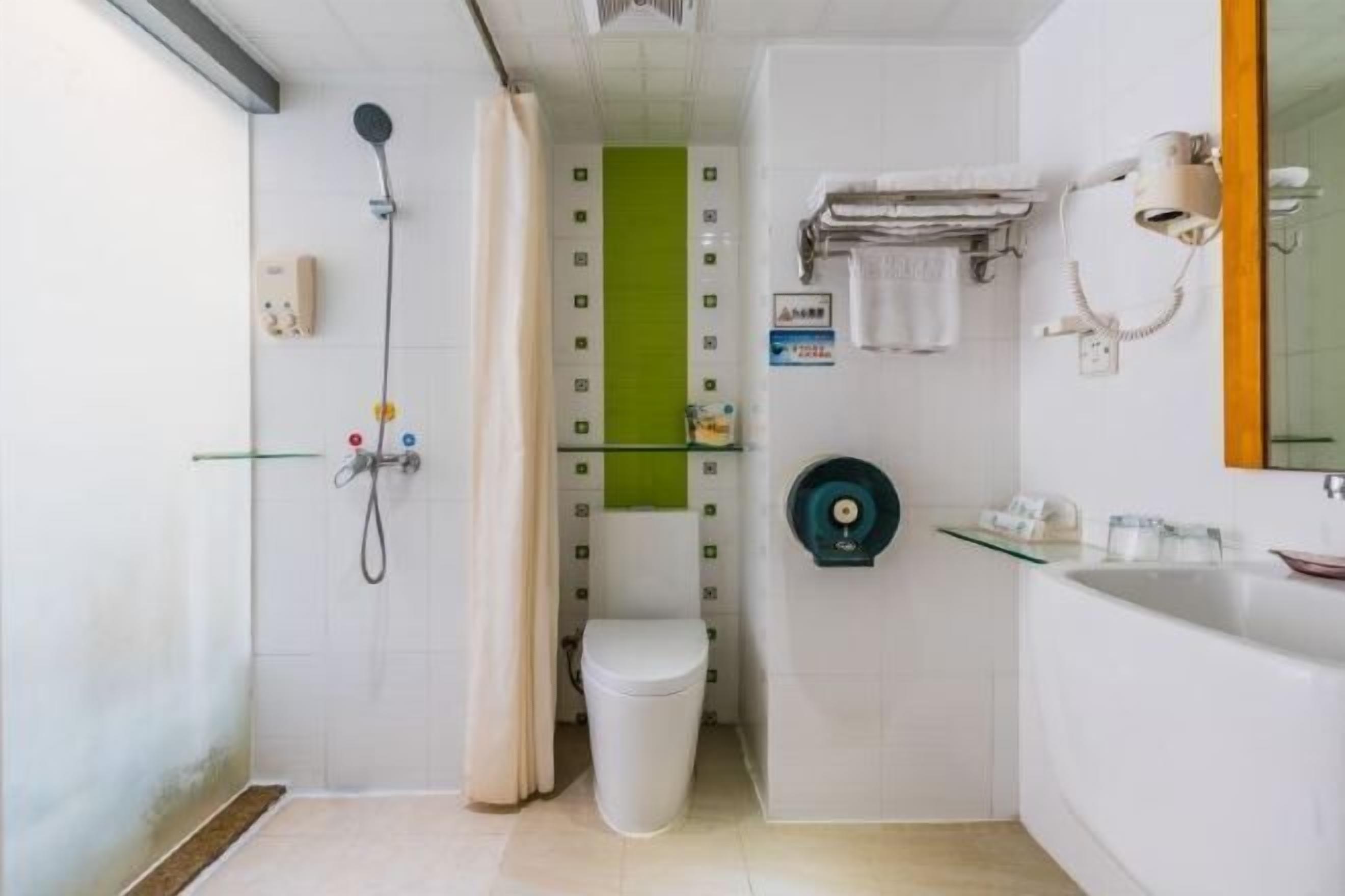 Une petite salle de bain compacte, équipée d’une douche, de toilettes et d’un lavabo.
