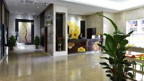 Eine moderne Lobby mit einer Rezeption, Topfpflanzen und einem großen Fenster.