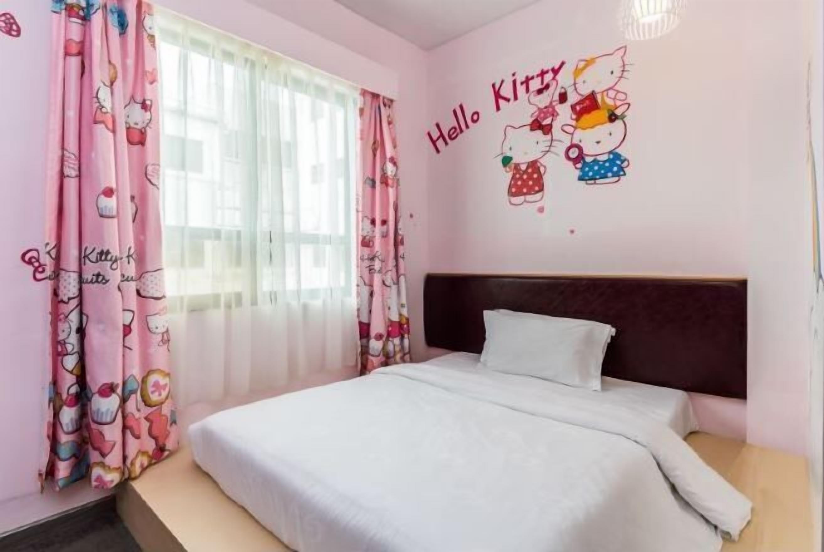 A pink-themed bedroom with a bed, curtains, and a wall decal featuring Hello Kitty characters.
