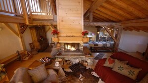 Un intérieur de chalet chaleureux avec une cheminée en pierre, des meubles en bois et un tapis en peau de vache.