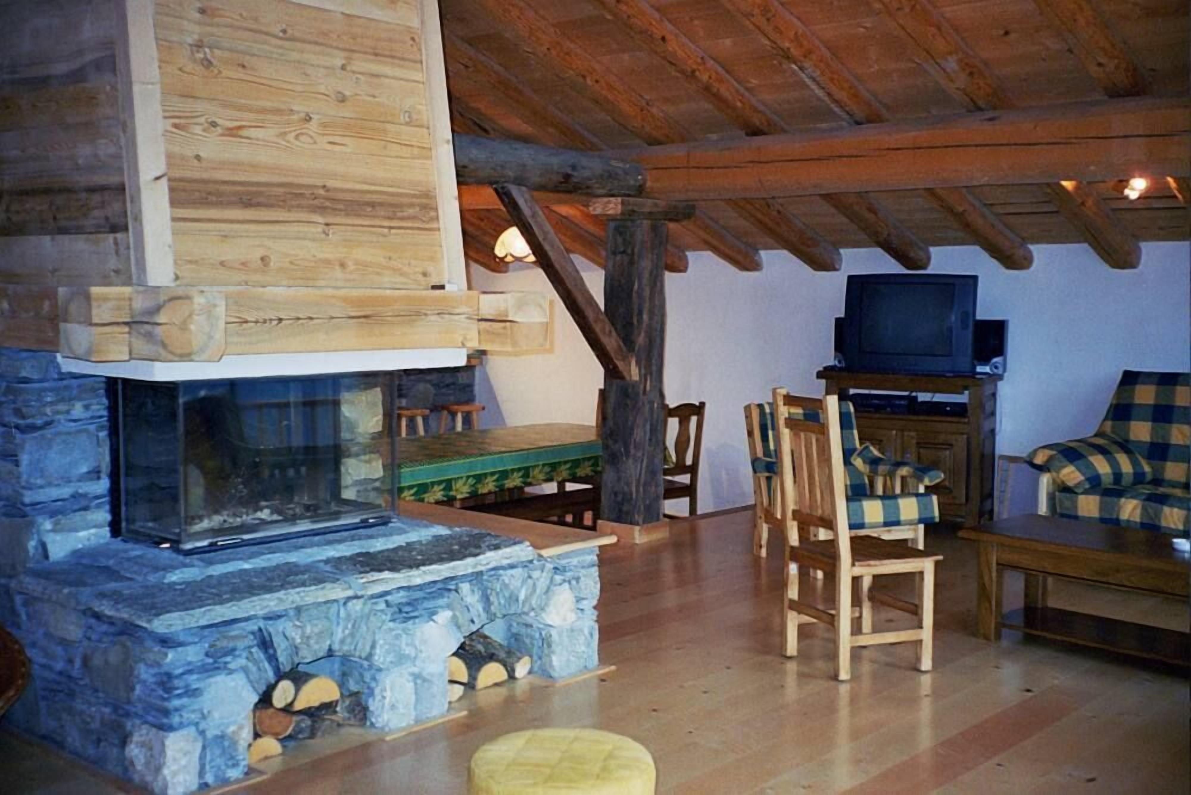 Una sala de estar acogedora con chimenea de piedra, muebles de madera y un televisor.