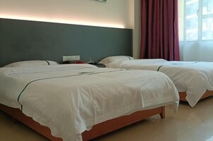 A hotel room with two beds, a nightstand, a lamp, and a window with curtains.