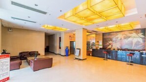 A hotel lobby with a reception desk, seating area, and a large wall mural.