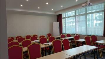 A conference room with multiple tables and chairs, a whiteboard, and a projector.
