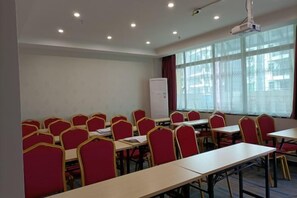 Ein Konferenzraum mit mehreren Tischen, Stühlen, einer Whiteboard-Tafel und einem Projektor.