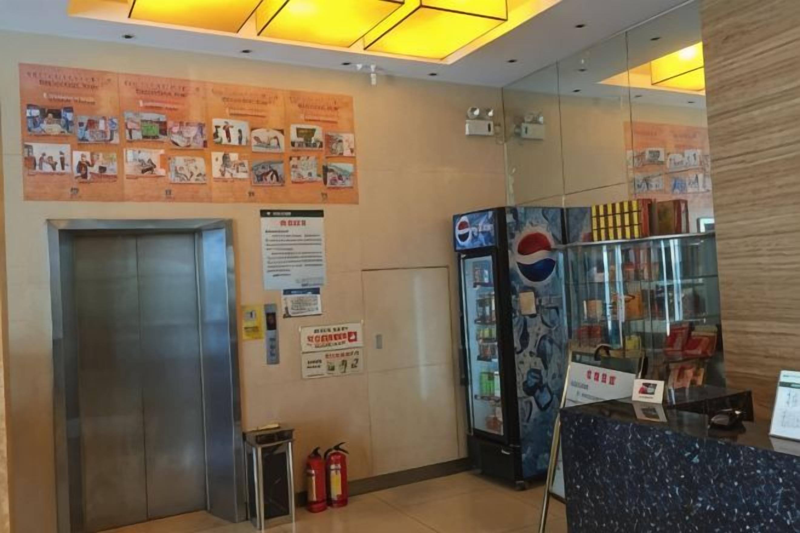 Un ascensor, un extintor, un refrigerador de Pepsi y un tablón de anuncios con diversos avisos.