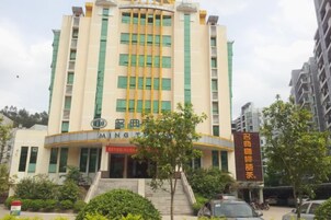 A multi-story building with a curved facade, a prominent entrance with steps, and signage indicating it is a hotel.