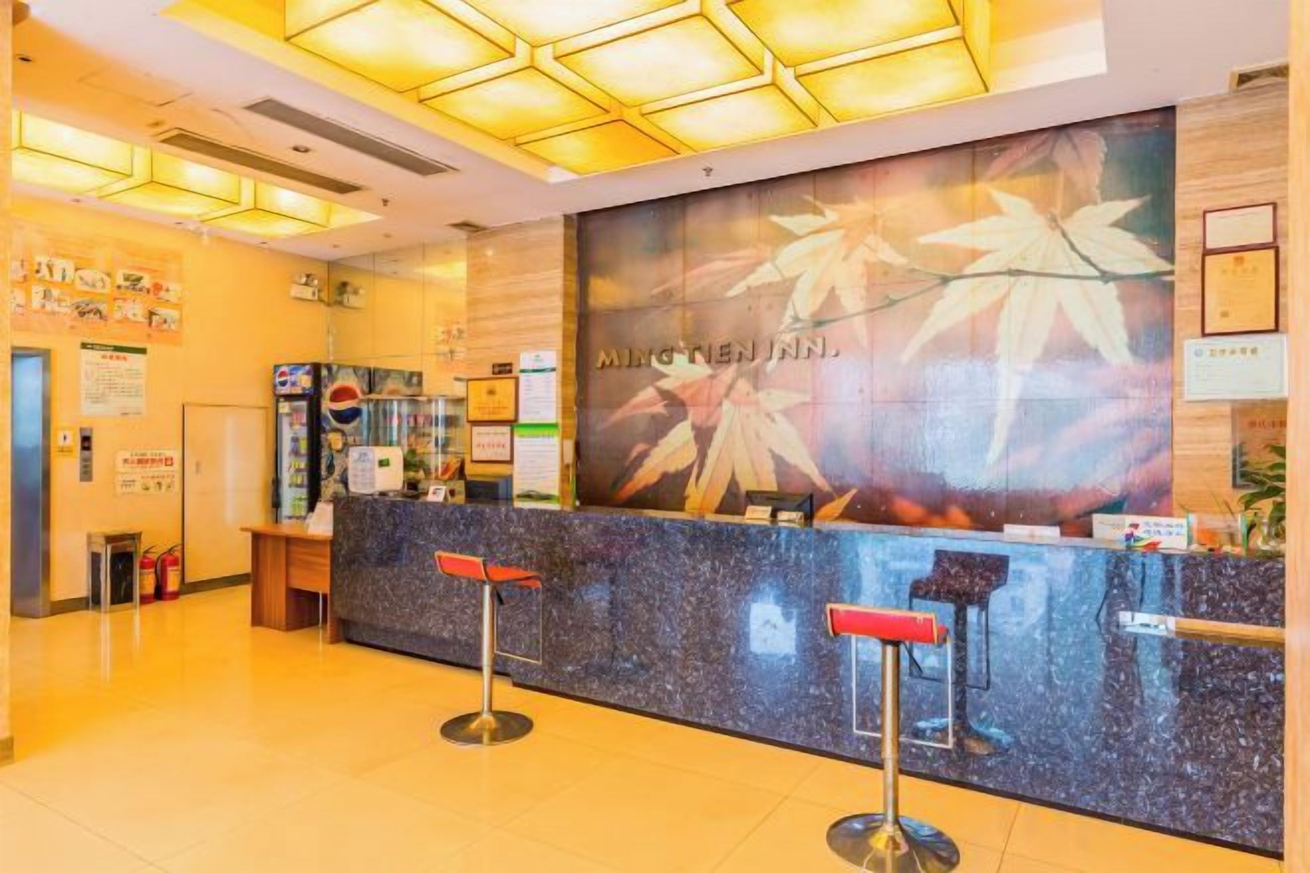 A reception area with a counter, two red bar stools, and a wall with a large poster.