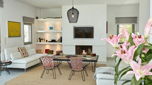 A modern living room with a white sofa, two patterned chairs, a coffee table, and a fireplace.