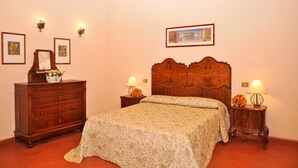 Ein Schlafzimmer mit einem hölzernen Bett, einem Schminktisch, zwei Nachttischen mit Lampen und gerahmten Bildern an den Wänden.