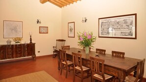 Ein Esszimmer mit Holztisch und -stühlen, einem Blumenstrauß und gerahmten Bildern an den Wänden.
