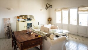 Ein Essbereich mit einem Holztisch, weißen Stühlen, einer weißen Kommode und einem an der Wand befestigten Fahrrad.