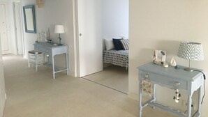 Une pièce comprenant un lit, un bureau et une chaise. Une porte donne accès à une autre pièce.