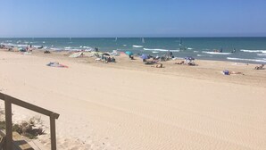 Une plage avec un ciel dégagé, un rivage sablonneux et des gens qui se détendent.