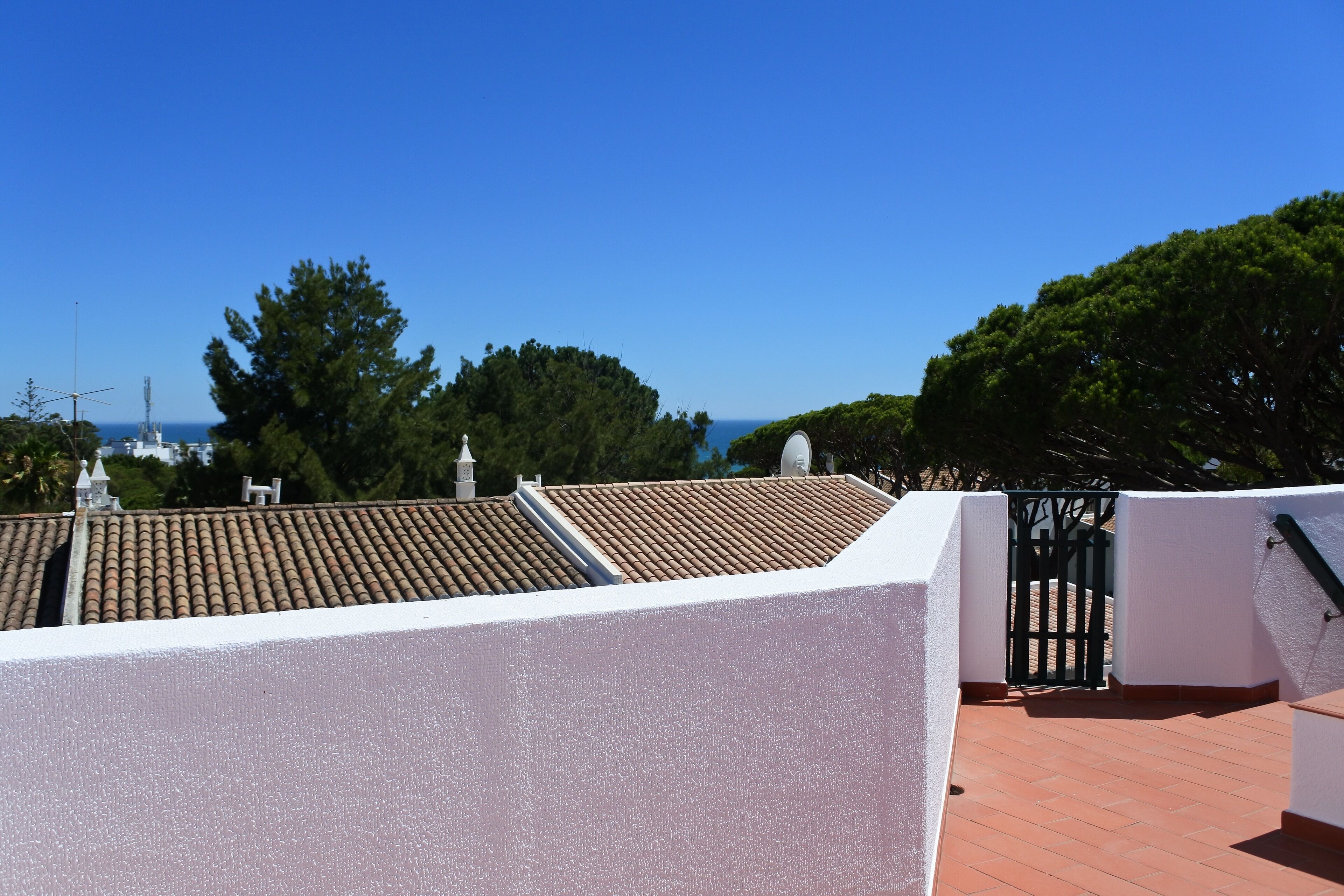 Terraço no telhado com telhado cerâmico, paredes brancas e vista para o mar.