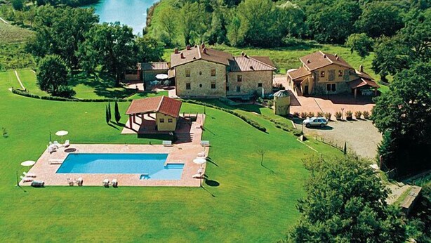 A large estate with a swimming pool, multiple buildings, and a lake.