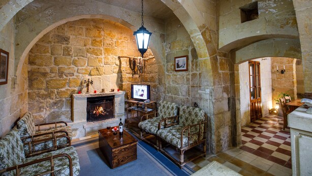A stone-walled room with a fireplace, wooden furniture, and a checkered floor. - Gozo, semi detached farmhouse with sunny terraces and free internet access. (Kercem)