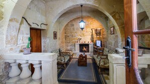 A stone-walled room with a fireplace, wooden furniture, and a television. - Gozo, semi detached farmhouse with sunny terraces and free internet access. (Kercem)
