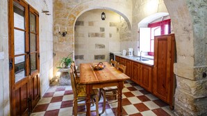 A rustic kitchen with a wooden table, stone walls, and a checkered floor. - Gozo, semi detached farmhouse with sunny terraces and free internet access. (Kercem)