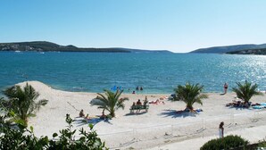 A beach with palm trees, people sunbathing, and boats in the water. - New apartments  near the sea   (Seget Donji)