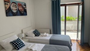 A hotel room with two beds, a window with curtains, a painting on the wall, and a view of the outside. - New apartments  near the sea   (Seget Donji)
