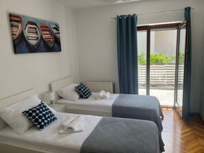 A hotel room with two beds, a window with curtains, a painting on the wall, and a view of the outside. - New apartments  near the sea   (Seget Donji)