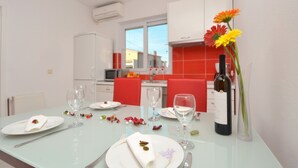 A dining table set with plates, cutlery, and wine bottles, with a window and red chairs in the background. - New apartments  near the sea   (Seget Donji)