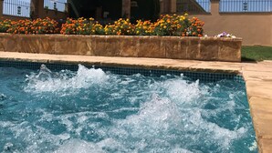 A swimming pool with water splashing, surrounded by a flower bed and a building with a tiled roof. - Spectacular house nestled among vineyards, less than 1 hour from Barcelona (Sant Marti Sarroca)