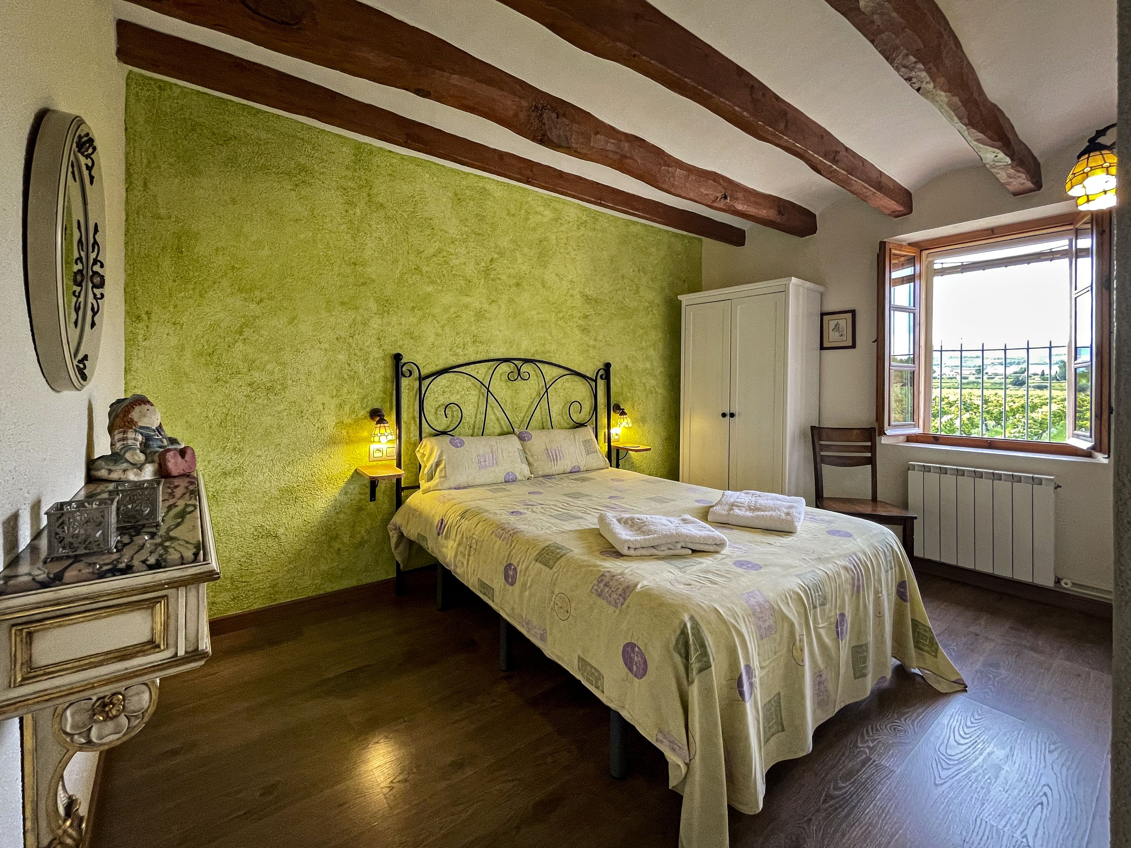 Een slaapkamer met een bed, nachtkastjes, een kledingkast en een raam met uitzicht.